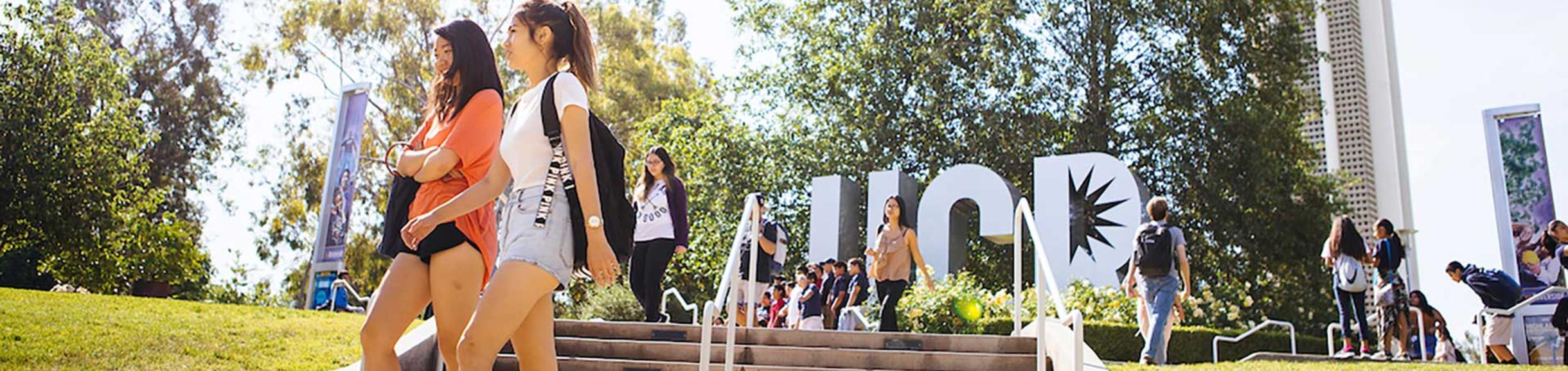 students walking near the UCR sign and Bell Tower
