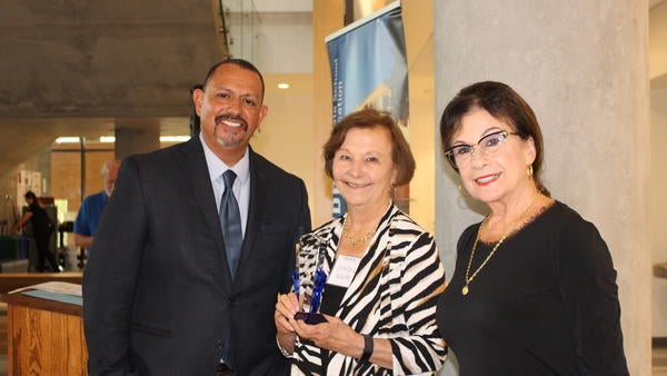 Interim Dean, Louie Rodriguez and presenter and alumna, Linda Scott Hendrick pose with Distinguished Alumni Honoree, Athena Waite