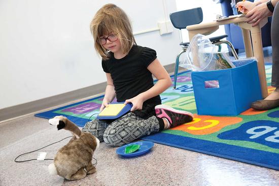 child playing with a remote control stuffed animal bunny with her teacher observing